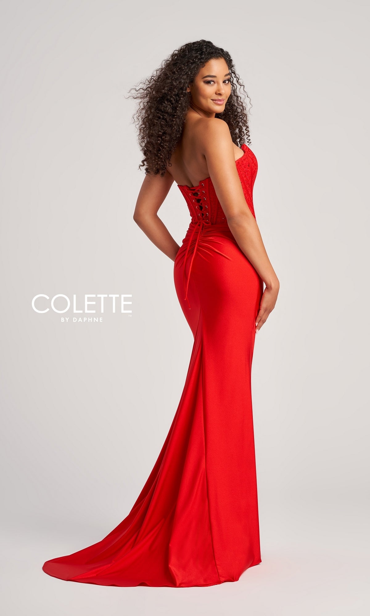 A woman poses in the Strapless Colette Long Designer Prom Dress CL5158, featuring a fitted silhouette, beaded corset bodice, and floor-length train against a plain light background. The text reads